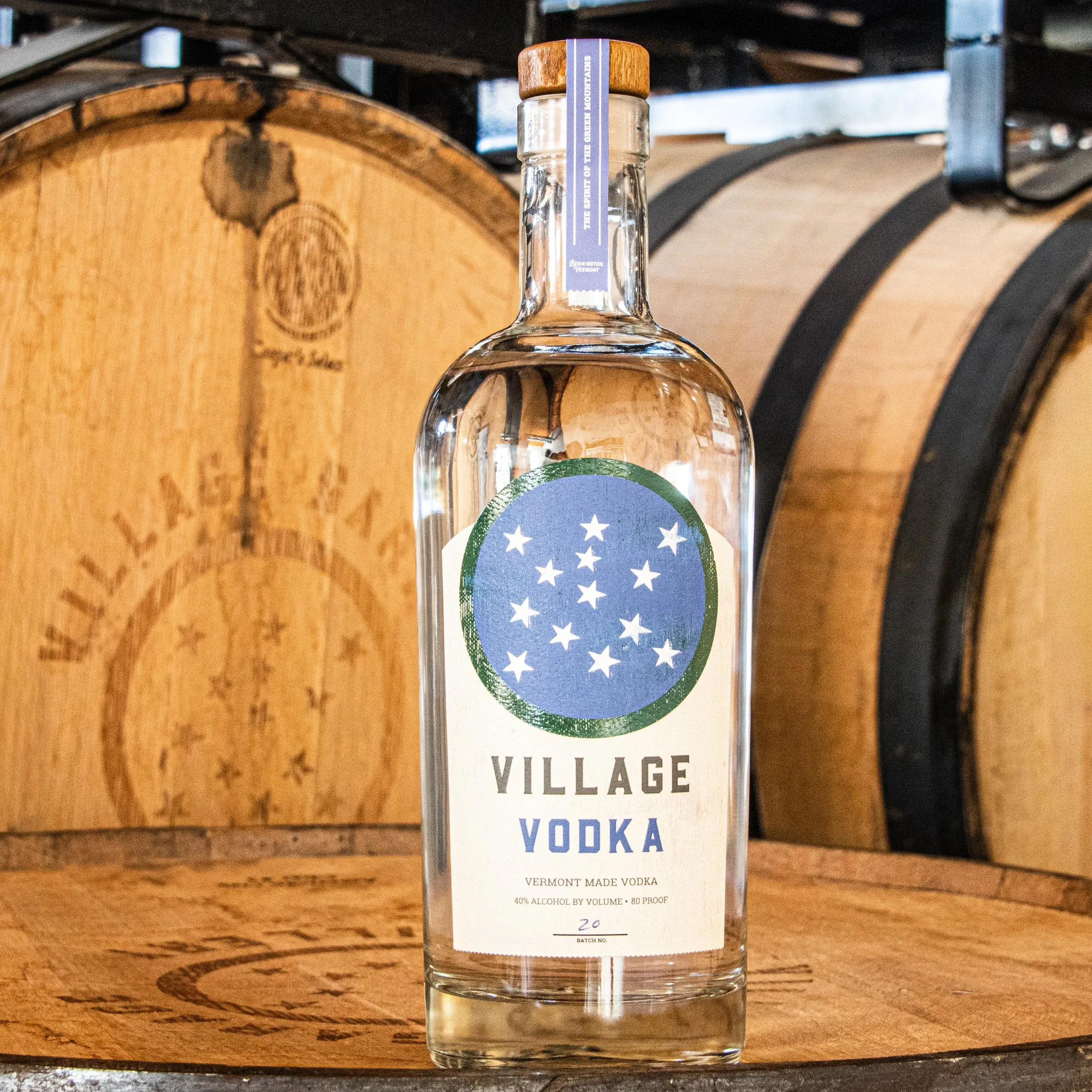Bottle of Village Vodka in front of oak barrels