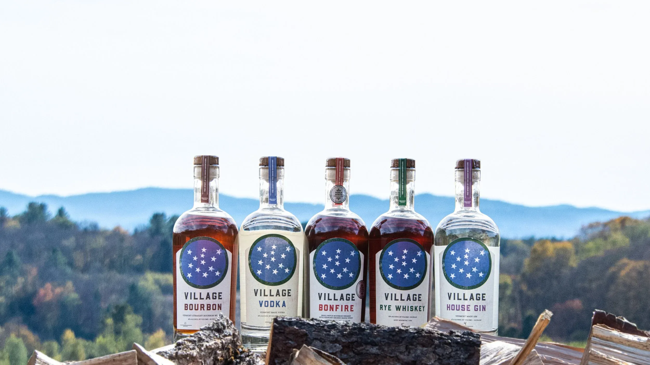 The Village Garage Distillery line-up of bottles against the Green Mountains